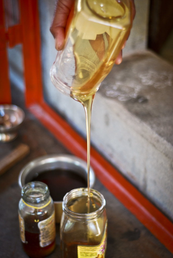 Photograph of golden honey being poured between glass jars, the classic vehicle of infant botulism spores