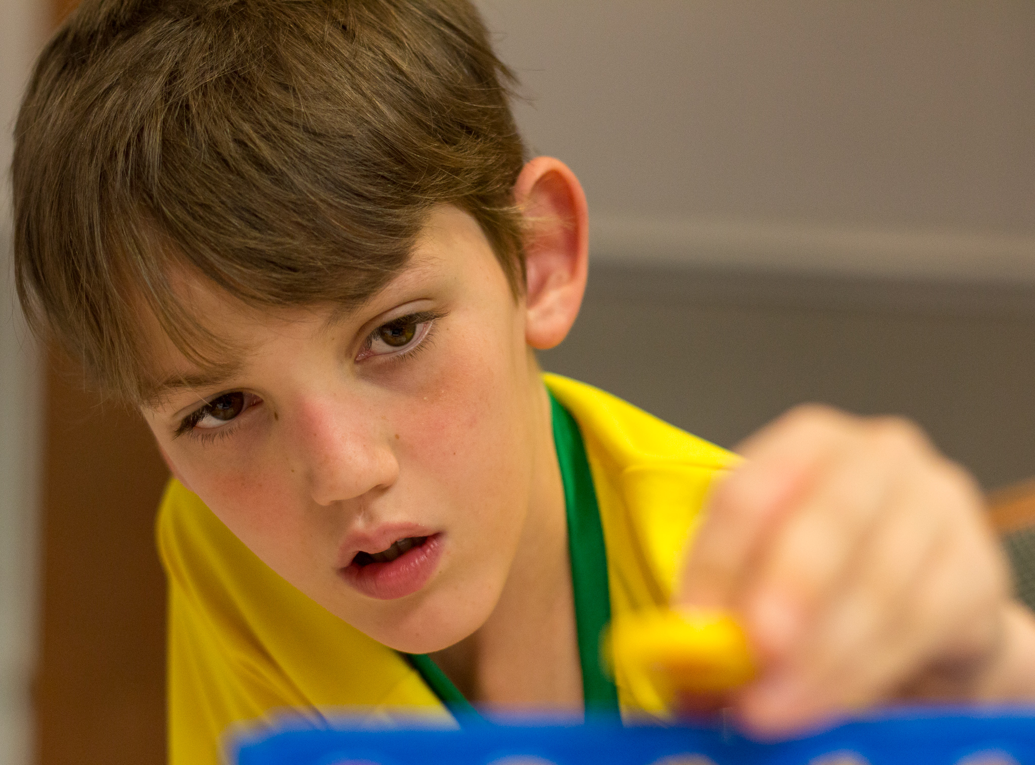 A boy plays with a toy with his head angled downward; one ear and much of the face are visible.